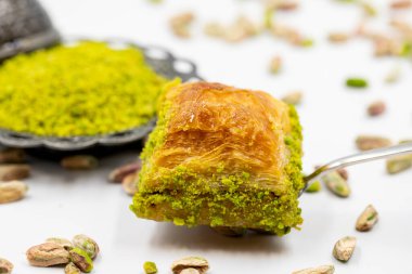 Çatalla çatallı, beyaz arka planda fıstıklı baklava. Geleneksel Türk mutfağı lezzetleri. Yakın plan Pistachio Baklava. Yerel adı kuru baklava