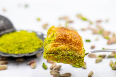 Çatalla çatallı, beyaz arka planda fıstıklı baklava. Geleneksel Türk mutfağı lezzetleri. Yakın plan Pistachio Baklava. Yerel adı kuru baklava