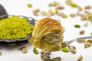 Çatalla çatallı, beyaz arka planda fıstıklı baklava. Geleneksel Türk mutfağı lezzetleri. Yakın plan Pistachio Baklava. Yerel adı Midye Baklava