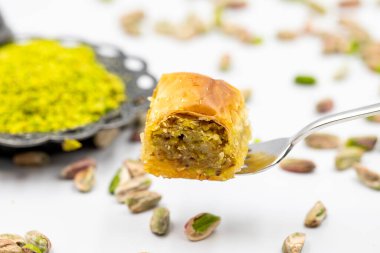 Çatalla çatallı, beyaz arka planda fıstıklı baklava. Geleneksel Türk mutfağı lezzetleri. Yakın plan Pistachio Baklava. Yerel adı fistikli baklava
