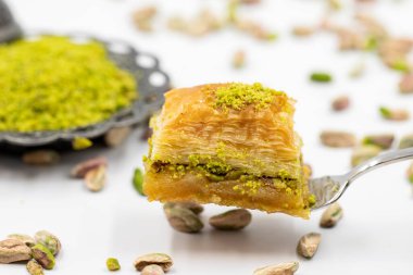 Çatalla çatallı, beyaz arka planda fıstıklı baklava. Geleneksel Türk mutfağı lezzetleri. Yakın plan Pistachio Baklava. Yerel adı kuru baklava
