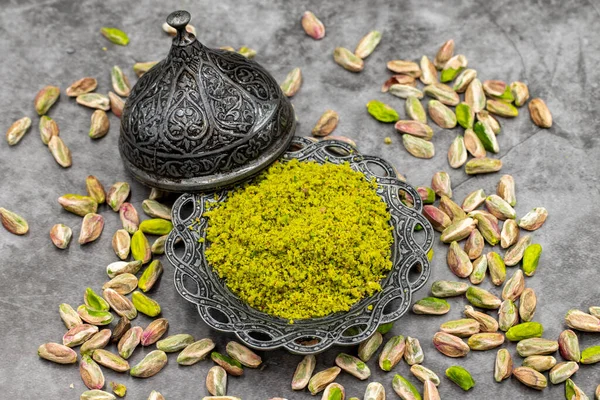 Koyu arkaplanda fıstık tozu. Fıstıklarla çevrili. Yakın plan. yerel adı toz antep fistik