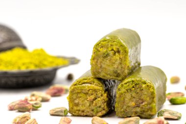 Beyaz arka planda fıstıkla kaplanmış baklava. Geleneksel Akdeniz mutfağı lezzetleri. Yakın plan şam fıstıklı baklava. yerel adı fistik sarma baklava