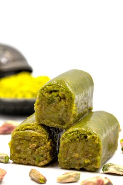 Beyaz arka planda fıstıkla kaplanmış baklava. Geleneksel Akdeniz mutfağı lezzetleri. Yakın plan şam fıstıklı baklava. yerel adı fistik sarma baklava