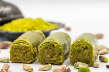Beyaz arka planda fıstıkla kaplanmış baklava. Geleneksel Akdeniz mutfağı lezzetleri. Yakın plan şam fıstıklı baklava. yerel adı fistik sarma baklava