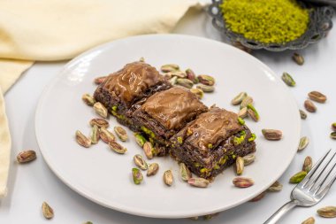 Beyaz arka planda fıstıklı çikolatalı baklava. Geleneksel Akdeniz mutfağı lezzetleri. Çikolatalı Baklava 'ya yakın çekim. Yerel adı cthe baklava