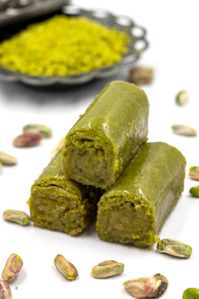 Beyaz arka planda fıstıkla kaplanmış baklava. Geleneksel Akdeniz mutfağı lezzetleri. Yakın plan şam fıstıklı baklava. yerel adı fistik sarma baklava