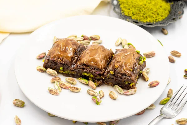 Beyaz arka planda fıstıklı çikolatalı baklava. Geleneksel Akdeniz mutfağı lezzetleri. Çikolatalı Baklava 'ya yakın çekim. Yerel adı cthe baklava