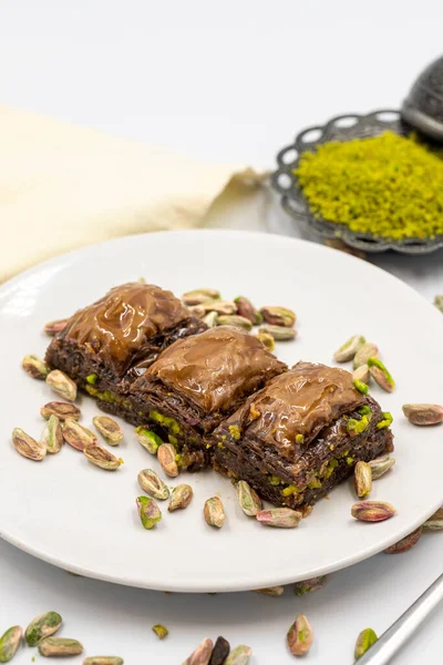 Beyaz arka planda fıstıklı çikolatalı baklava. Geleneksel Akdeniz mutfağı lezzetleri. Çikolatalı Baklava 'ya yakın çekim. Yerel adı cthe baklava