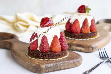 Çilekli pasta. Ortası kremayla dolu, etrafı çileklerle çevrili, beyaz bir arka planda. Fırın ürünleri. Kapat.