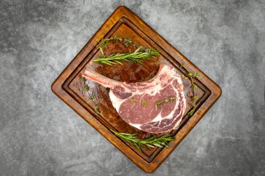 Esmer arka planda çiğ dana pirzolası. Tahta servis tahtasında çiğ dana pirzolası. Üst Manzara. Kapat.