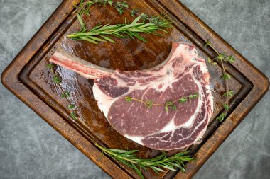 Esmer arka planda çiğ dana pirzolası. Tahta servis tahtasında çiğ dana pirzolası. Üst Manzara. Kapat.