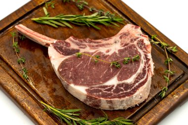 Beyaz arka planda çiğ dana pirzolası izole edilmiş. Çiğ dana pirzolası servis tahtası. Kapat.