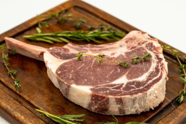 Beyaz arka planda çiğ dana pirzolası izole edilmiş. Çiğ dana pirzolası servis tahtası. Kapat.