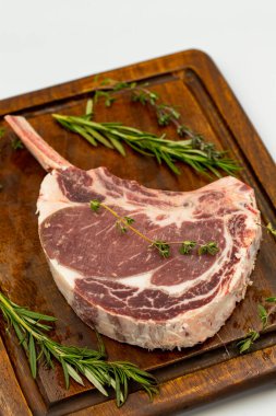 Beyaz arka planda çiğ dana pirzolası izole edilmiş. Çiğ dana pirzolası servis tahtası. Kapat.