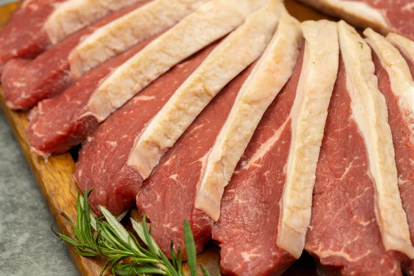 Karanlık bir arka planda biftek fileto. Tahta servis tahtasına çiğ sığır filetosu. Kapat.