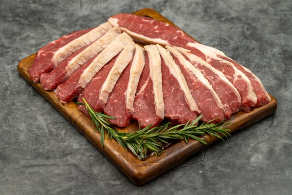 Karanlık bir arka planda biftek fileto. Tahta servis tahtasına çiğ sığır filetosu. Kapat.