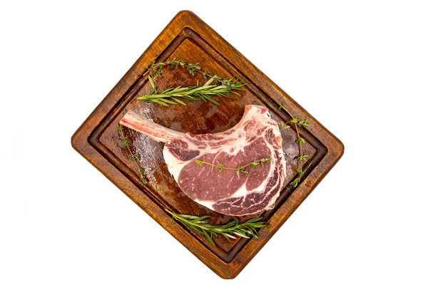 Beyaz arka planda çiğ dana pirzolası izole edilmiş. Tahta servis tahtasında çiğ dana pirzolası. Üst Manzara. Kapat.