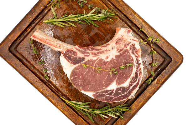 Beyaz arka planda çiğ dana pirzolası izole edilmiş. Tahta servis tahtasında çiğ dana pirzolası. Üst Manzara. Kapat.