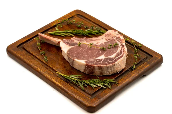 Beyaz arka planda çiğ dana pirzolası izole edilmiş. Çiğ dana pirzolası servis tahtası. Kapat.