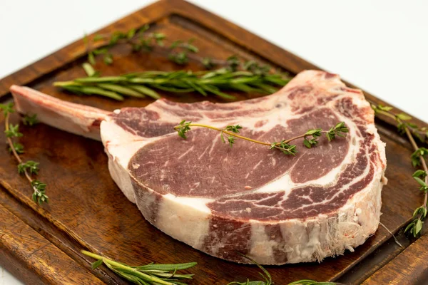 Beyaz arka planda çiğ dana pirzolası izole edilmiş. Çiğ dana pirzolası servis tahtası. Kapat.