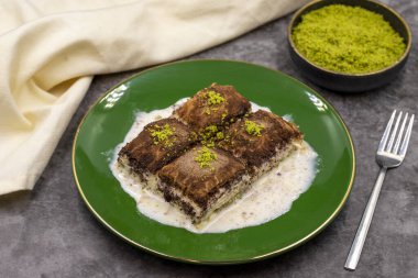 Koyu çikolata baklavası. Siyah arka planda süt olan baklava. Akdeniz mutfağı lezzetlidir. Yakın plan. Yerel adı: Acı soguk baklava