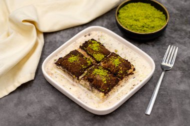 Koyu çikolata baklavası. Siyah arka planda süt olan baklava. Akdeniz mutfağı lezzetlidir. Yakın plan. Yerel adı: Acı soguk baklava