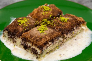 Koyu çikolata baklavası. Siyah arka planda süt olan baklava. Akdeniz mutfağı lezzetlidir. Yakın plan. Yerel adı: Acı soguk baklava