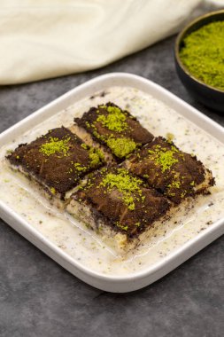 Koyu çikolata baklavası. Siyah arka planda süt olan baklava. Akdeniz mutfağı lezzetlidir. Yakın plan. Yerel adı: Acı soguk baklava