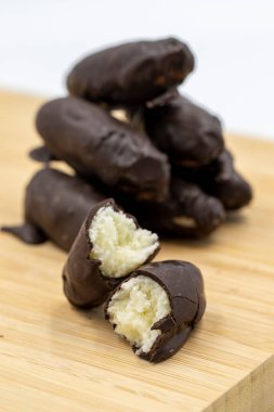 İçi hindistan cevizli, dışı koyu çikolatalı. Ahşap arka planda hindistan cevizli siyah çikolata. Kapat.