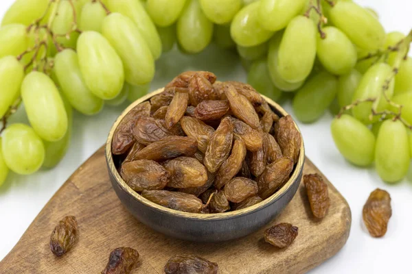 Beyaz arka planda kuru üzümler. Çiğ üzüm ve kuru üzüm. Sağlıklı ve taze fındık. Yakın plan. Yerel adı besni uzum