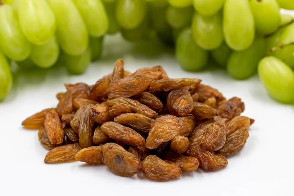 Beyaz arka planda kuru üzümler. Çiğ üzüm ve kuru üzüm. Sağlıklı ve taze fındık. Yakın plan. Yerel adı besni uzum