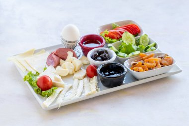 Geleneksel kahvaltı tabağı - zengin çeşit peynir, domates, salatalık, yumurta, ahşap zemin üzerinde reçel