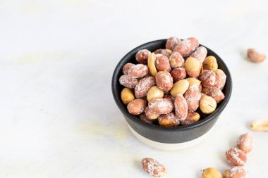 Beyaz ahşap arka planda, kasede tuzlanmış fıstık.