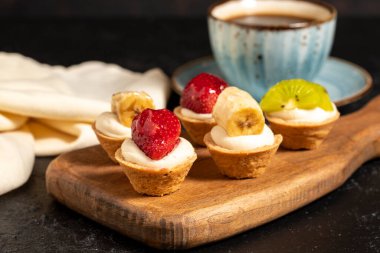 Meyveli tart. Koyu arkaplanda çilek, kivi ve muzlu tart. Kapat.