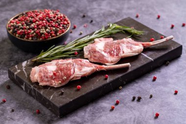 Karanlık arka planda kuzu pirzolası. Baharatlı çiğ kuzu pirzolası. Kapat.