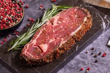 Siyah arka planda sığır pirzolası. Baharatlı taze çiğ biftek. Kapat.