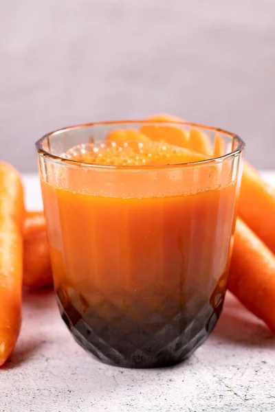 Carrot juice. Freshly squeezed juice. Freshly squeezed carrot juice in glass on stone background. Close-up