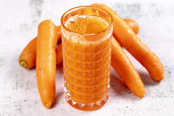 Carrot juice. Freshly squeezed juice. Freshly squeezed carrot juice in glass on stone background. Close-up