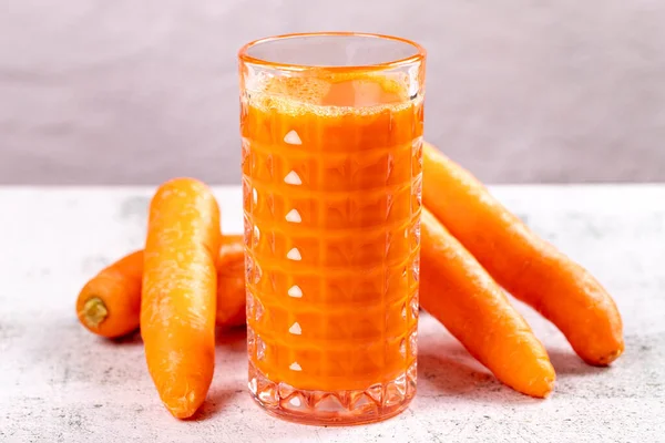 Carrot juice. Freshly squeezed juice. Freshly squeezed carrot juice in glass on stone background. Close-up