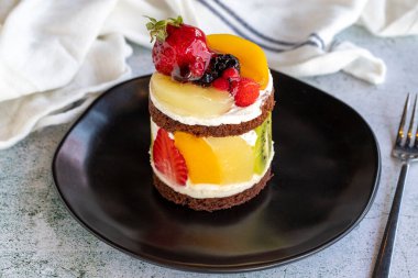 Meyveli kek. Taş zeminde meyvelerle çevrili bir pasta. Pastane ürünleri. Yakın plan..