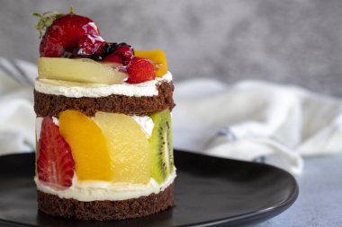 Meyveli kek. Taş zeminde meyvelerle çevrili bir pasta. Pastane ürünleri. Yakın plan..