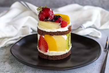 Meyveli kek. Taş zeminde meyvelerle çevrili bir pasta. Pastane ürünleri. Yakın plan..