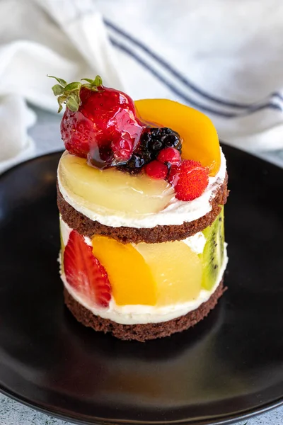 Fruit cake. Cake surrounded by fruits on a stone background. Patisserie products. Close-up.