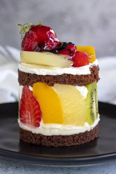 Meyveli kek. Taş zeminde meyvelerle çevrili bir pasta. Pastane ürünleri. Yakın plan..