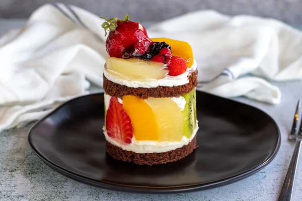 Fruit cake. Cake surrounded by fruits on a stone background. Patisserie products. Close-up.