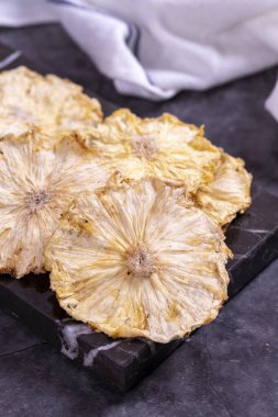 Kurutulmuş ananas dilimleri. Koyu arkaplanda dilimlenmiş ananas. Kurutulmuş meyve. Kapat.