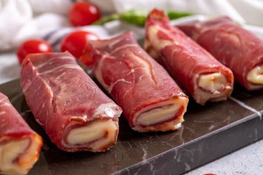 Peynirli pastırma. Çedarla doldurulmuş pastırma, taş zeminde ızgara domuz pastırması. Et barbekü için özel olarak hazırlandı. Kapat.