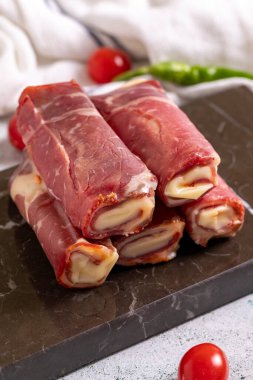 Peynirli pastırma. Çedarla doldurulmuş pastırma, taş zeminde ızgara domuz pastırması. Et barbekü için özel olarak hazırlandı. Kapat.