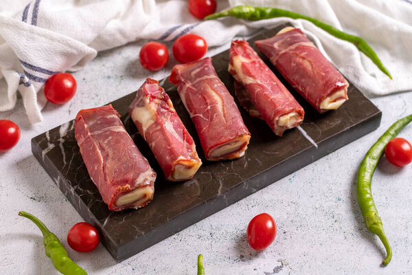 Cheese Pastrami. Pastrami stuffed with cheddar, grilled bacon on a stone floor. Meat specially prepared for barbecue. close up